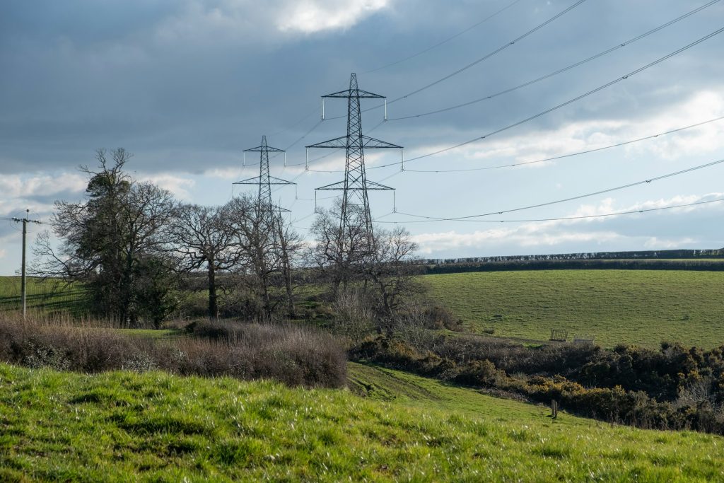Electricity pylons and power lines across green fields in Devon